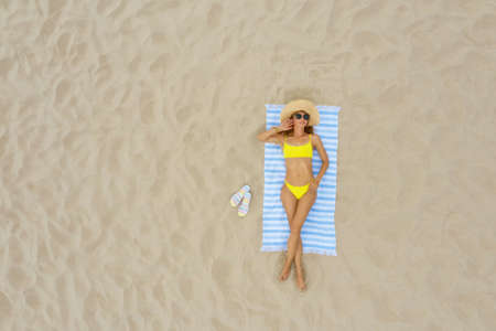 Woman sunbathing on beach towel at sandy coast, aerial view. Space for textの写真素材