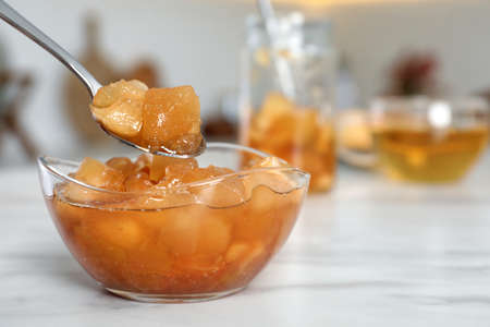 Spoon with delicious apple jam over bowl on white table, closeupの写真素材