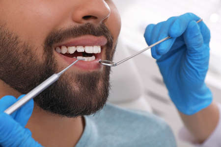 Dentist examining young man's teeth in clinic, closeupの写真素材