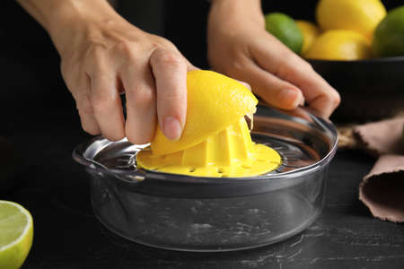 Woman squeezing lemon juice at black table, closeupの写真素材