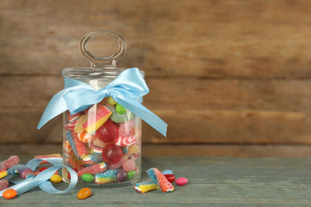 Jar with different delicious candies on light blue wooden table, space for textの写真素材