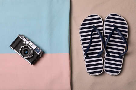 Beach towel, camera and flip flops on sand, flat layの写真素材