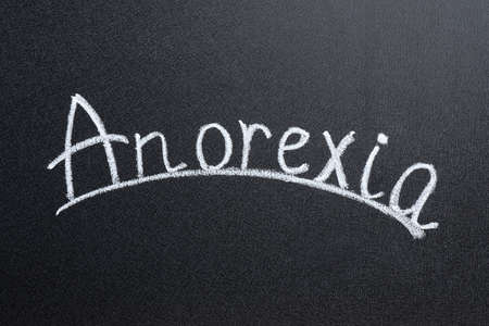 Word Anorexia written with white chalk on blackboardの写真素材