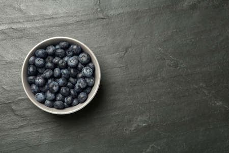 Ceramic bowl with blueberries on black table, top view and space for text. Cooking utensilの写真素材