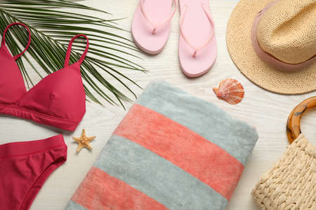 Towel and different beach accessories on white wooden background, flat layの写真素材