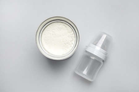 Can of powdered infant formula with feeding bottle on light background, flat lay. Baby milkの写真素材