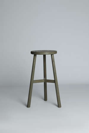 Stylish wooden stool on light gray background. Interior element