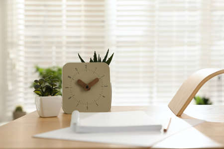 Notebook, clock and houseplants on table indoors