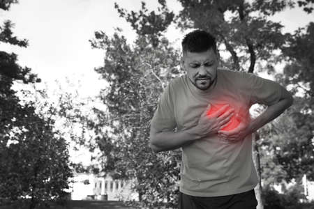 Man having heart attack in park. Black and white photo