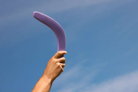 Man throwing boomerang against blue sky, closeup. Space for textの写真素材