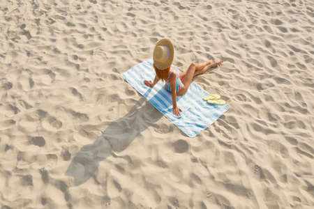 Woman sunbathing on beach towel at sandy coastの写真素材