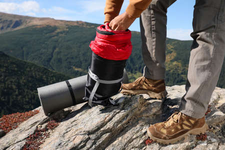 Tourist holding sleeping bag on mountain peak, closeup