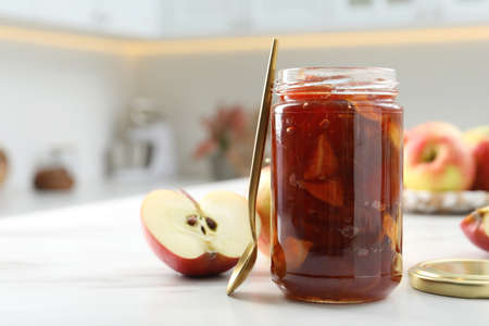 Delicious apple jam in jar and fresh fruit on white table. Space for textの写真素材