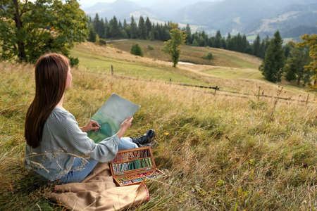 Young woman drawing landscape with soft pastels in nature. Space for textの写真素材