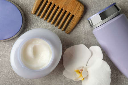 Hair care cosmetic products, orchid flower and comb on gray table, flat layの写真素材