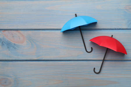 Small color umbrellas on light blue wooden background, flat lay. Space for textの写真素材