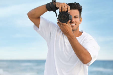 Photographer taking picture with professional camera near seaの写真素材