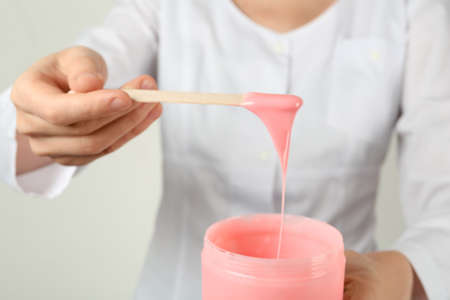 Woman holding spatula with hot depilatory wax, closeupの写真素材