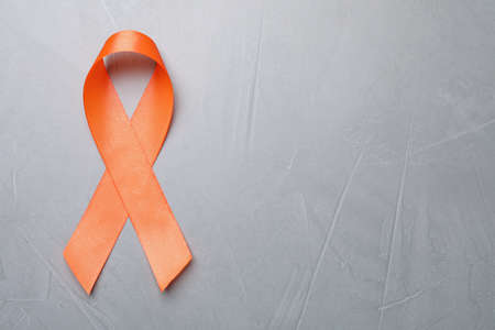 Orange ribbon on light gray table, top view with space for text. Multiple sclerosis awarenessの写真素材