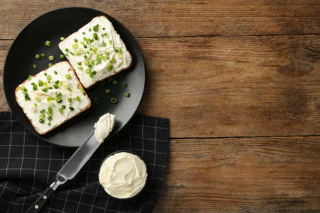 Delicious sandwiches with cream cheese and chives on wooden table, flat lay. Space for textの写真素材