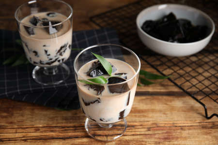 Glass of milk with grass jelly and green leaf on wooden tableの写真素材