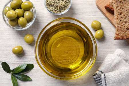 Glass bowl with fresh olive oil on white wooden table, flat layの写真素材