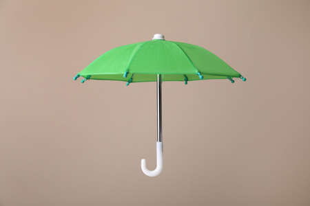 Open small green umbrella on beige backgroundの写真素材
