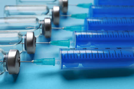 Disposable syringes with needles and vials on light blue background, closeupの写真素材