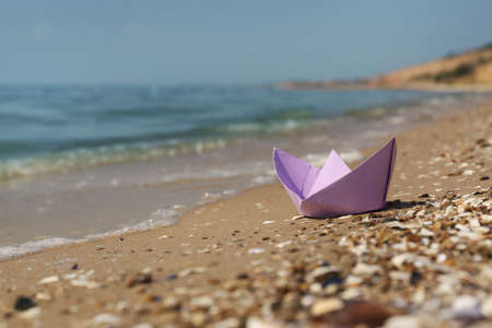 Paper boat on sandy beach near sea, space for textの写真素材