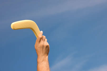Man throwing boomerang against blue sky, closeup. Space for textの写真素材