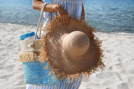Woman with beach bag and straw hat near sea on sunny day, closeupの写真素材