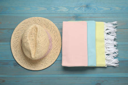 Beach towel and straw hat on light blue wooden background, flat layの写真素材