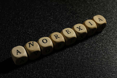 Word Anorexia made of wooden cubes on black background, closeupの写真素材