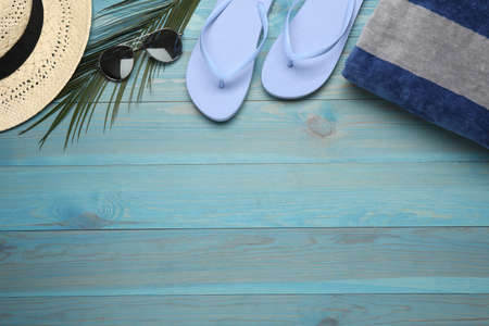 Beach towel, straw hat, flip flops and sunglasses on light blue wooden background, flat lay. Space for textの写真素材