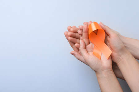 Couple holding orange ribbon on light gray background, top view with space for text. Multiple sclerosis awarenessの写真素材