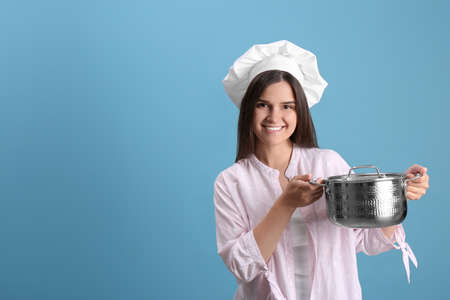 Happy young woman with cooking pot on light blue background. Space for textの写真素材