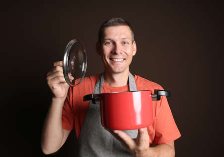 Happy man with cooking pot on brown backgroundの写真素材