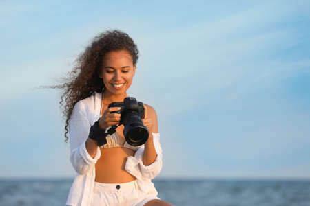 African American photographer with professional camera near seaの写真素材