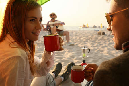Friends resting on sandy beach. View from camping tentの写真素材
