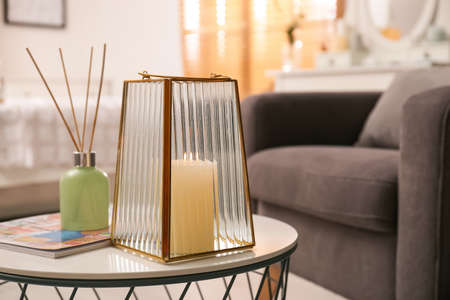 Stylish holder with burning candle and reed air freshener on table in roomの写真素材