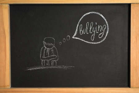 Blackboard with phrase Stop Bullying and drawing of sad human, closeupの写真素材