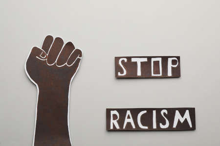 Phrase Stop Racism near paper hand with clenched fist on light background, flat layの写真素材