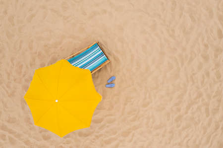 Yellow beach umbrella, sunbed and flip flops on sandy coast, aerial view. Space for textの写真素材