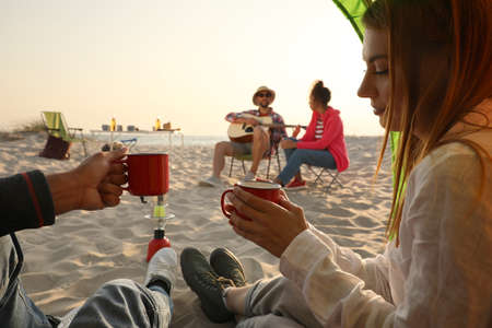 Friends resting on sandy beach. View from camping tentの写真素材