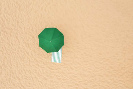 Green beach umbrella and towel on sandy coast, aerial view. Space for textの写真素材