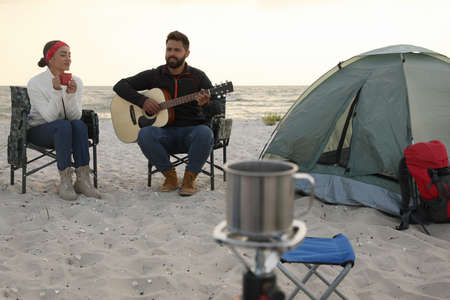 Lovely couple resting near camping tent on sandy beachの写真素材
