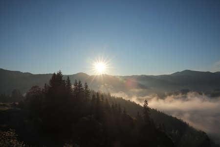 Beautiful view of mountains covered with fog at sunriseの写真素材