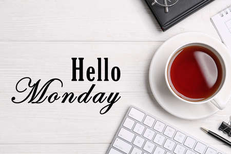 Hello Monday, start your week with good mood. Cup of tea and office stationery on white wooden table, flat layの写真素材