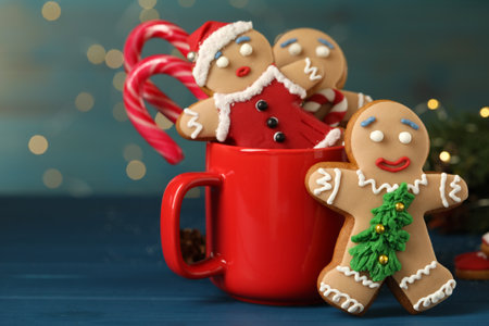Delicious homemade Christmas cookies with cup on blue wooden table against blurred festive lights