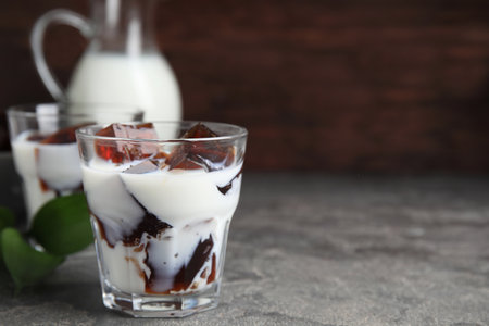 Glasses of milk with delicious grass jelly on gray table, closeup. Space for textの写真素材